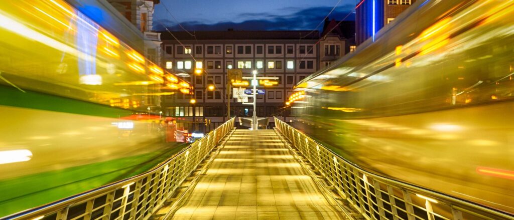 Fußgängerbrücke mit Lichtspuren der Stadtbahn in Hannover bei Nacht